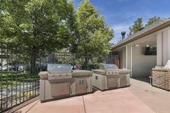 Two bbqs on a patio in front of a house